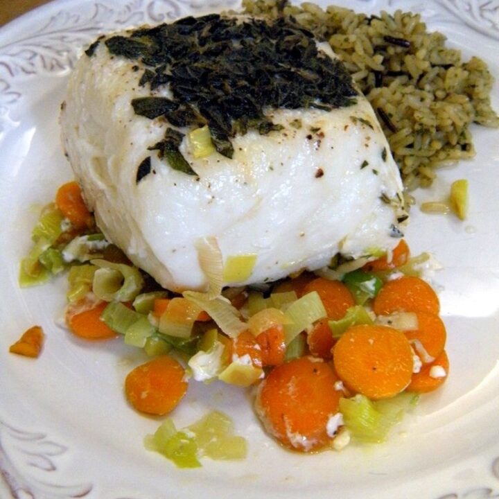 A piece of cooked Halibut over leeks and carrots.