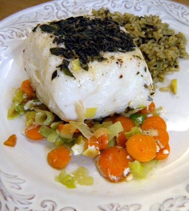 A piece of cooked Halibut over leeks and carrots. 