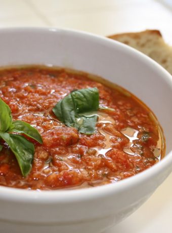 A white bowl filled with tomato pappa al pomodoro topped with basil.