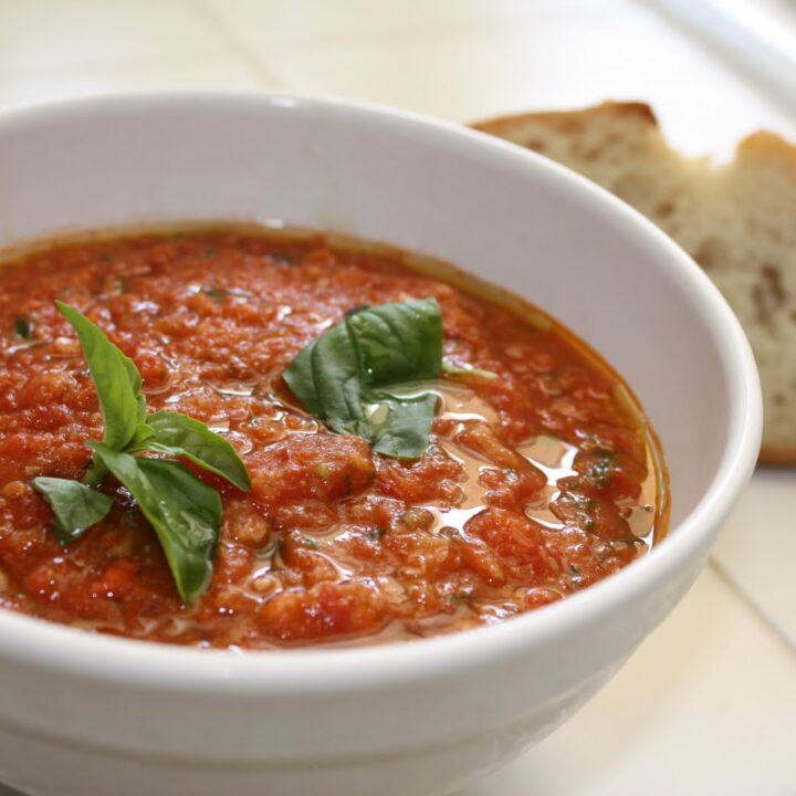 A white bowl filled with tomato pappa al pomodoro topped with basil.