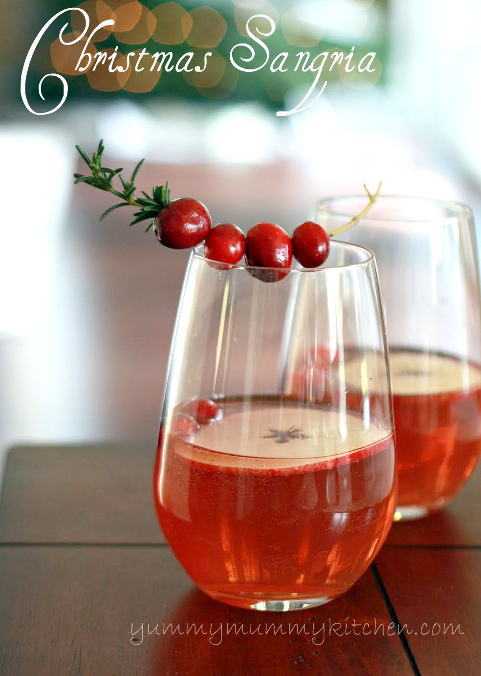 Two glasses filled with sparkling sangria with cranberry juice garnished with rosemary, fresh cranberries, and apple slices. 