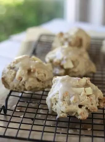 Apple oatmeal scones on a cooling rack are covered with a maple glaze.