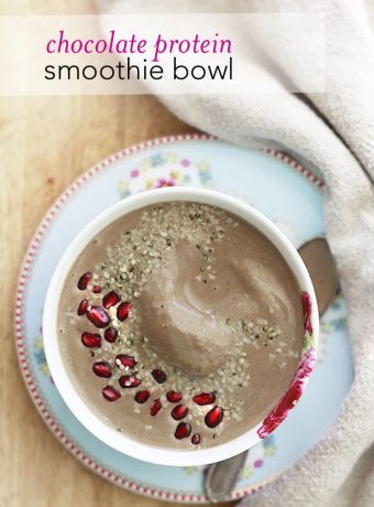 A creamy chocolate smoothie bowl topped with pomegranate seeds and hemp seeds.