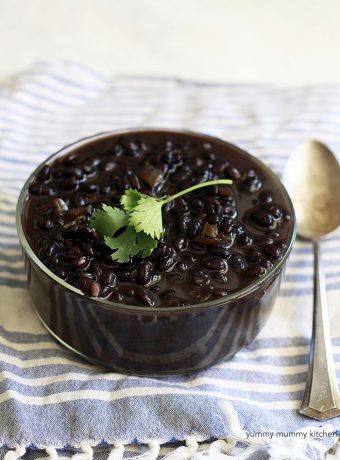 A large bowl of homemade black beans with a sprig of cilantro