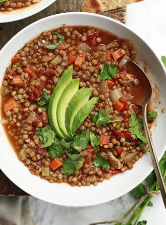 A bowl of Mexican lentil soup topped with avocado.