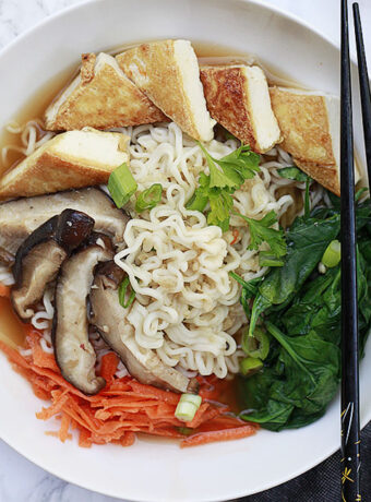A bowl of vegetarian and vegan ramen with spinach, tofu. mushrooms and carrots.