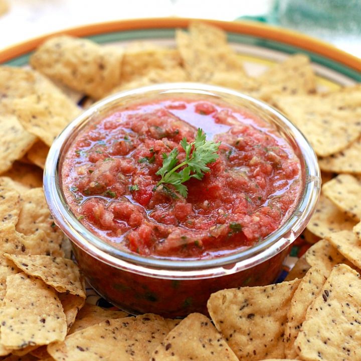 A bowl of salsa with made with fresh tomatoes served with chips.