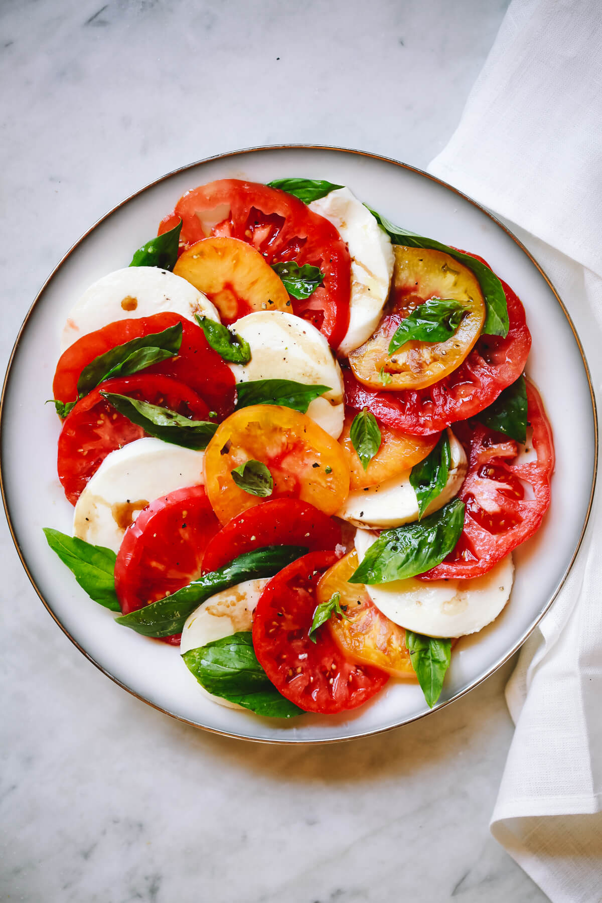 A plate of Caprese salad made with fresh tomatoes, mozzarella, and basil.