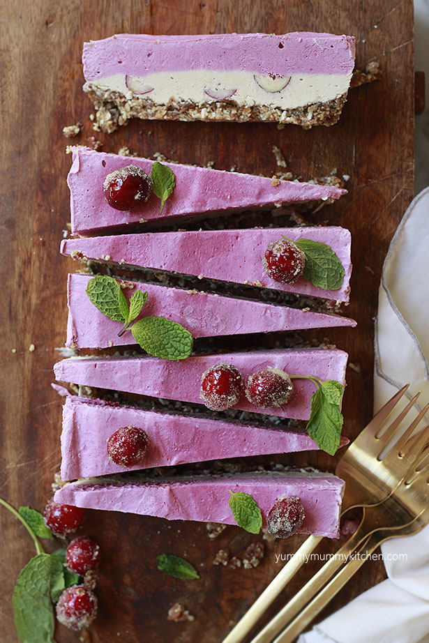 Vegan cranberry cheesecake slices layered with pink and white and a nut date crust. 