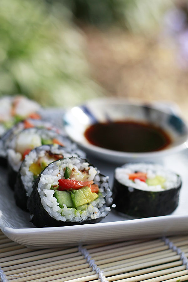 A beautiful photograph of a vegan sushi roll filled with cucumber, avocado, and bell pepper. 