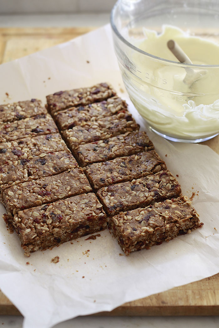 Homemade peanut butter granola bars recipe getting cut into squares on parchment paper. 