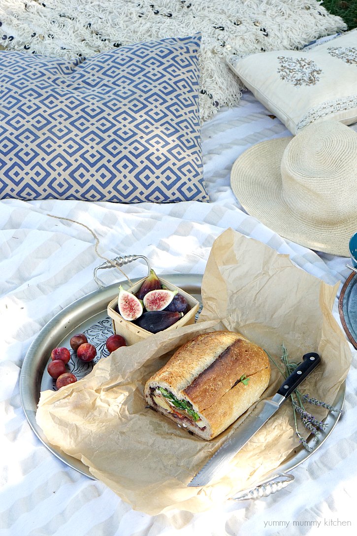 A vegan stuffed muffaletta sandwich with vegetables and tapenade is perfect for a backyard picnic. 
