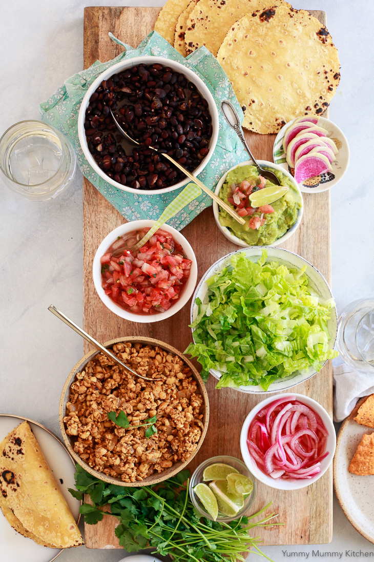 A vegan tempeh taco bar with soft tortillas, black beans, salsa, lettuce, and pickled onions. Tempeh tacos make a great vegan taco dinner. 