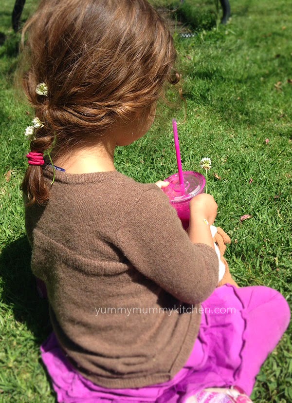 Little girl holding a pink pitaya smoothie. 
