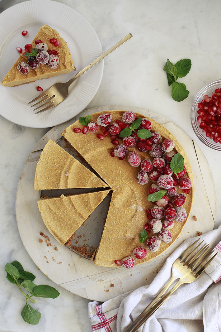 An overhead photo of a vegan pumpkin cheesecake topped with sugared cranberries.