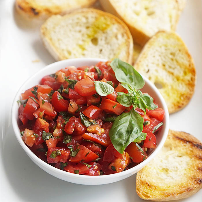 A bowl of traditional Italian tomato bruschetta served with grilled bread. 