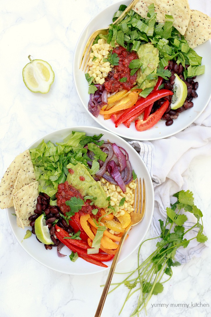 Vegan fajita bowls with quinoa, peppers, onions, and veggies and topped with guacamole and salsa. 
