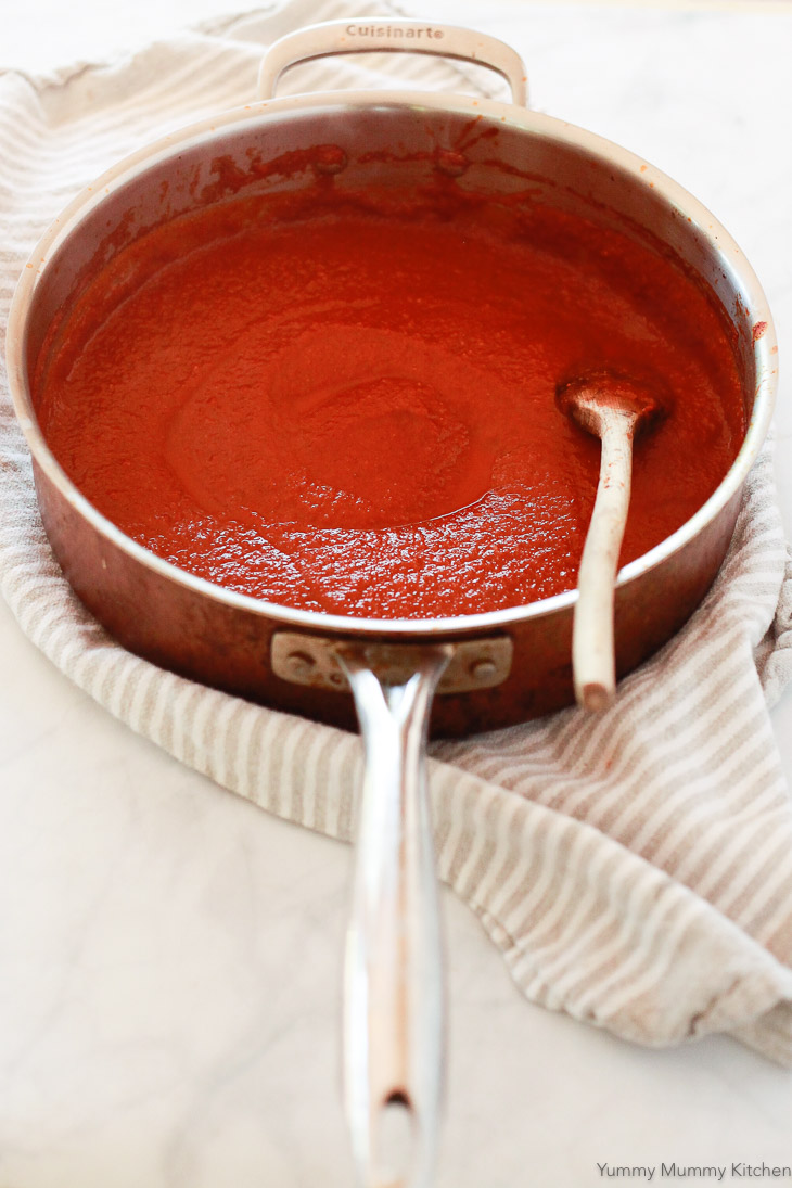 A large sauce pan filled with homemade red enchilada sauce. This easy enchilada sauce recipe gets blended in the blender and then simmered on the stove. 