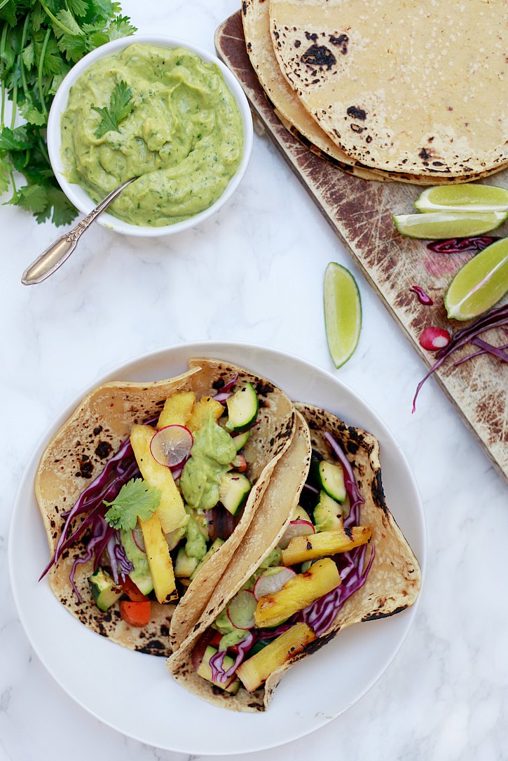 Grilled vegetable tacos and black bean tacos topped with avocado cream sauce, cabbage, sliced radishes, and grilled pineapple makes a beautiful and healthy dinner. 
