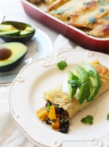 A butternut squash and black bean enchilada topped with avocado and sour cream.