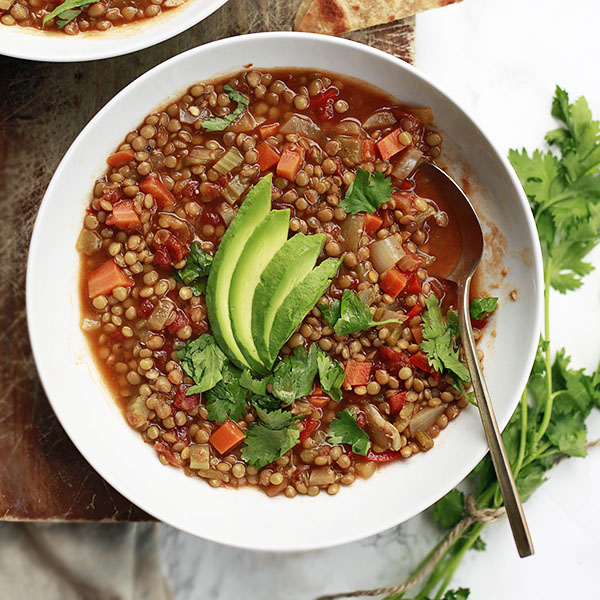 A bowl of lentejas (Mexican lentil soup) topped with avocado and cilantro. 