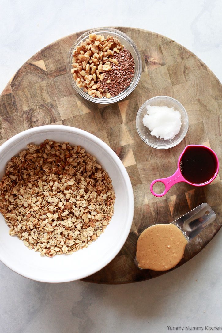 Ingredients for crunchy homemade no-bake granola bars include pre-made granola, peanut butter, maple syrup, flax, and coconut oil. 
