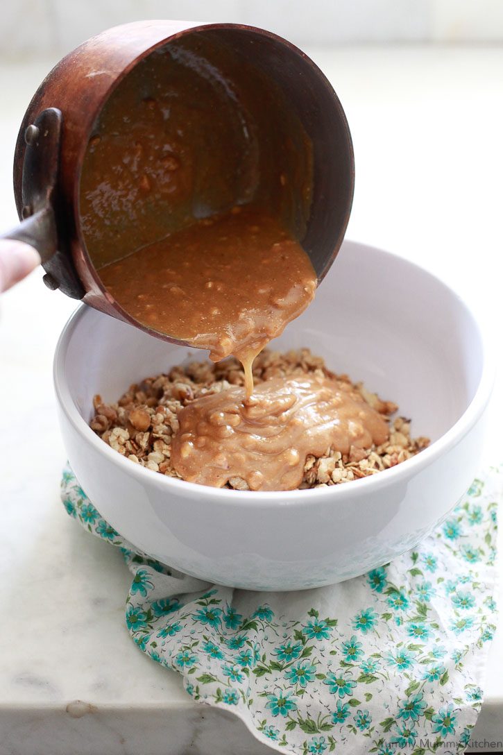 Melted peanut butter and maple syrup get poured over granola for homemade crunchy granola bars. 