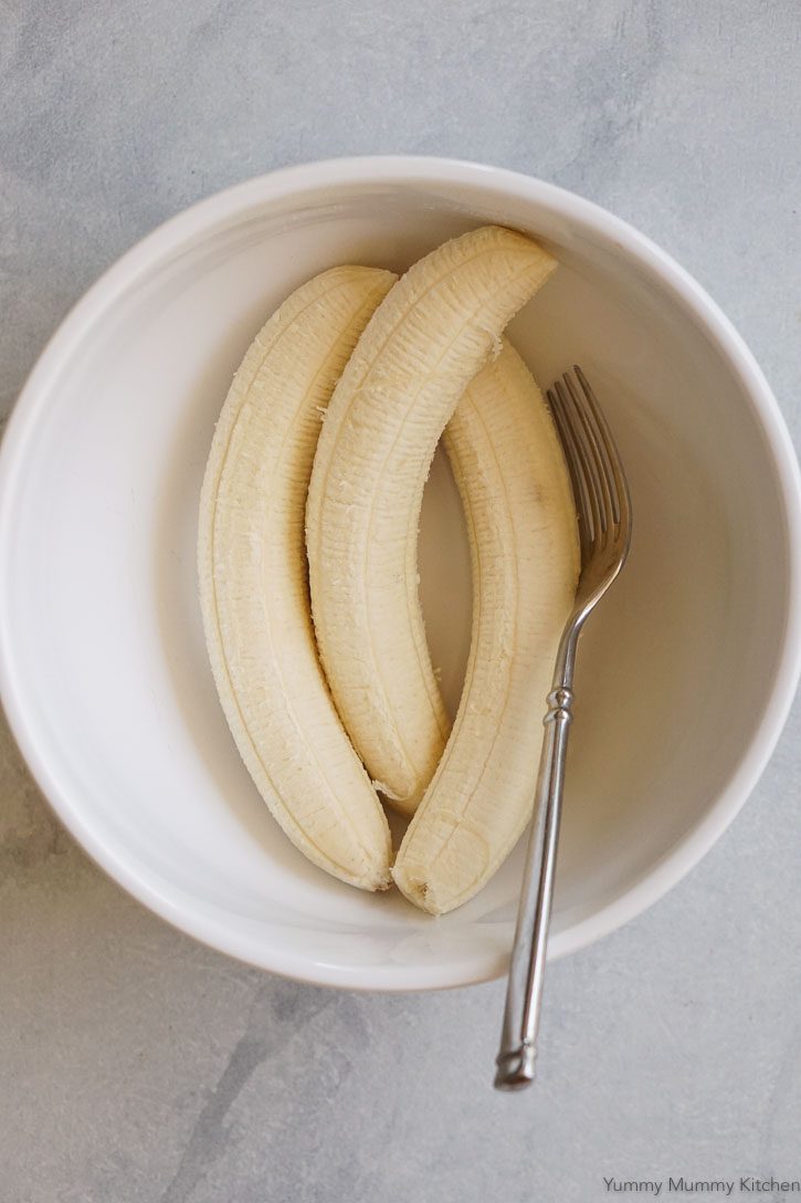 Three peeled bananas in a white bowl ready to be mashed. 