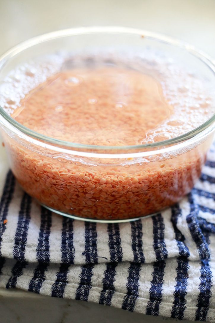 A bowl of red lentils soaking in water. Lentils don't need to be soaked, but should be rinsed and sorted before cooking. 