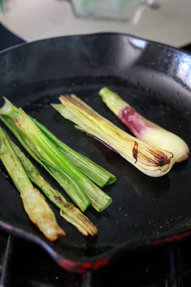 Spring onions get charred on a stovetop skillet. 