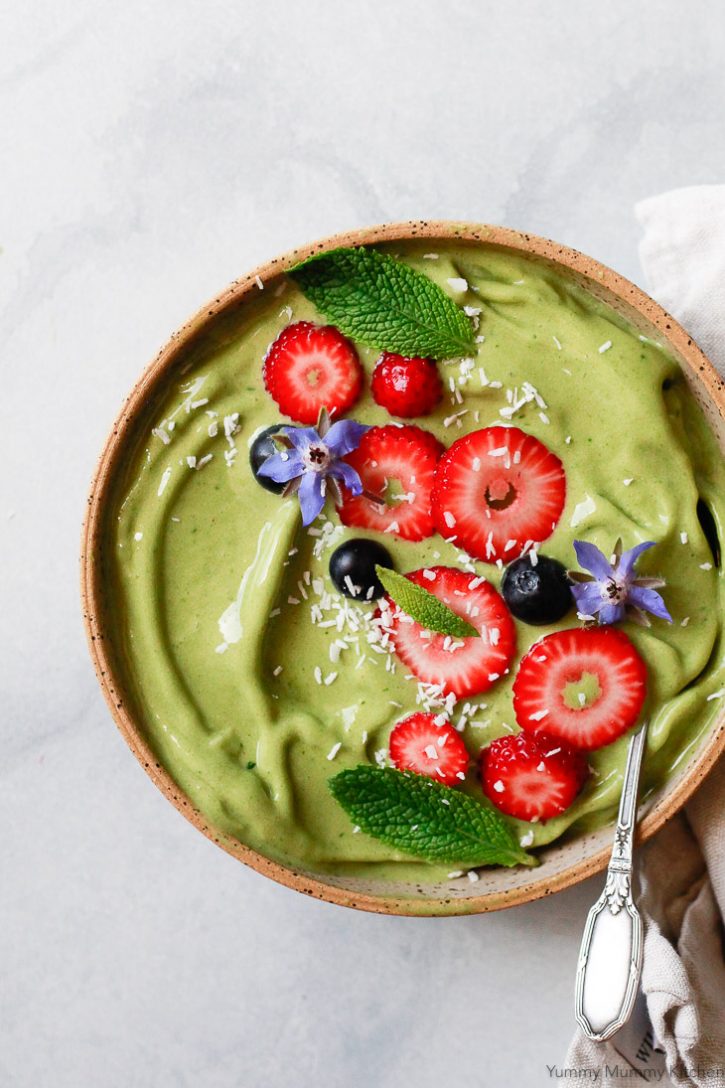 Green matcha smoothie bowl recipe topped with strawberries, blueberries, mint. This matcha smoothie recipe is delicious in a bowl or glass. 