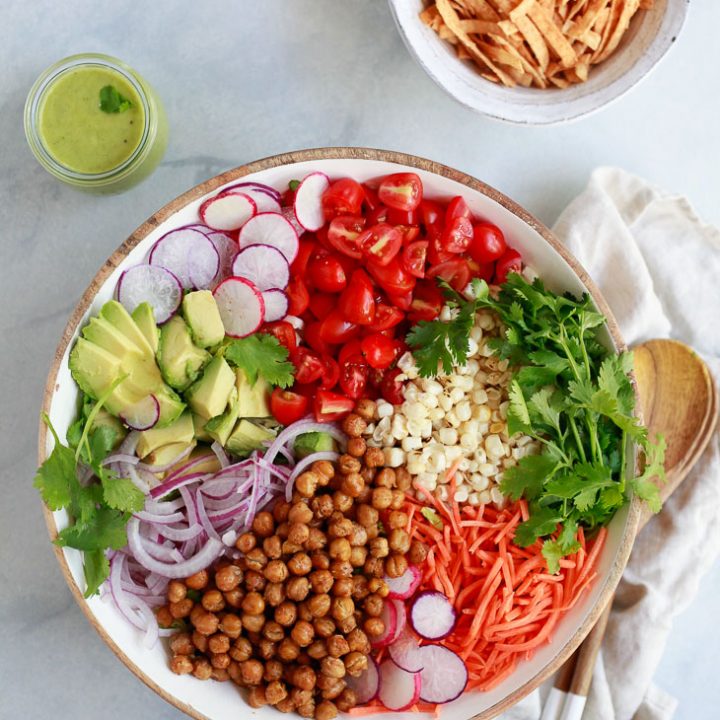 A big beautiful Southwestern salad with corn, roasted chickpeas, tomatoes, romaine, and avocado dressing.