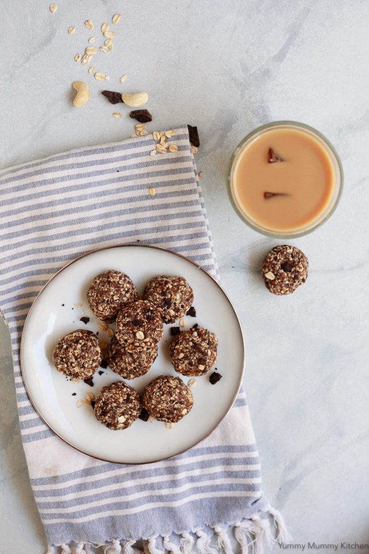 A plate of healthy no-bake oatmeal cookies on a white plate with a cup of iced coffee. 