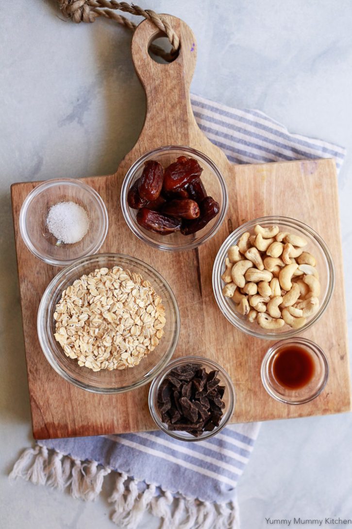 Ingredients for healthy no-bake oatmeal cookies include oats, dates, cashews, maple syrup, and dark chocolate. 