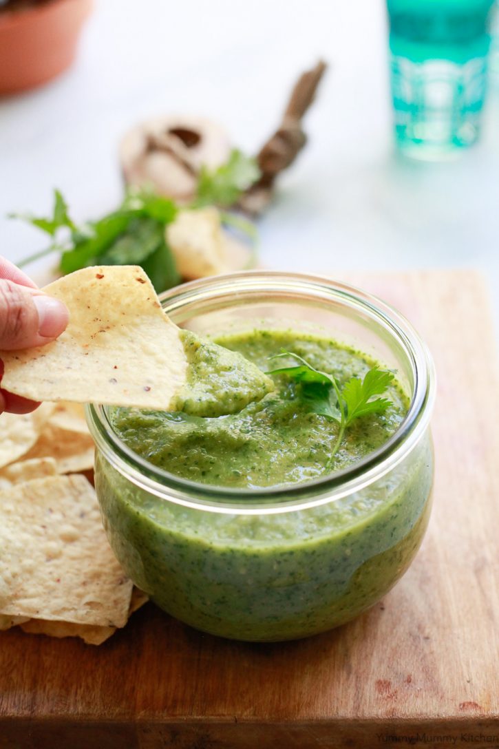 Roasted Tomatillo Salsa Verde in a glass jar with chips. 
