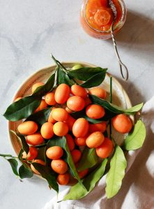 A bowl of freshly picked kumquats sits on a white countertop.