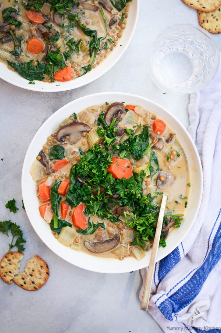 A large bowl filled with creamy mushroom vegan lentil soup topped with parsley. 