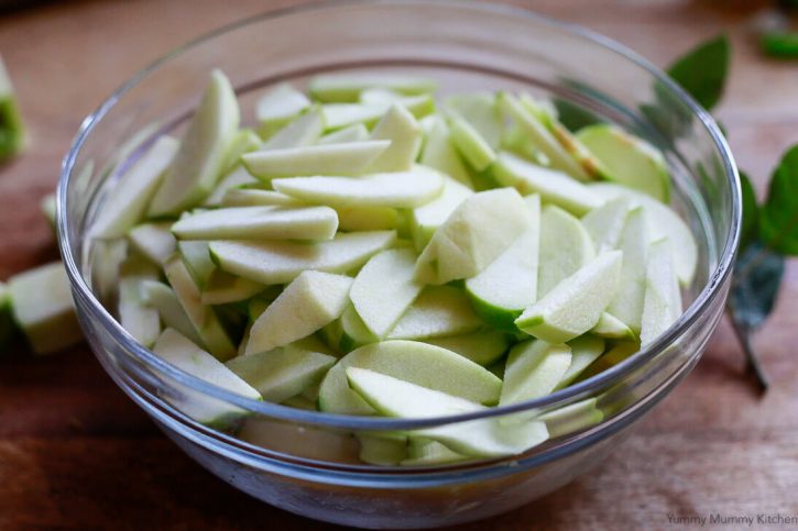 Thinly sliced granny smith apples in a bowl for making vegan apple pie. 