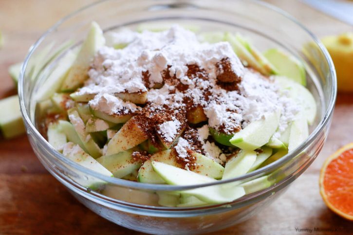 Coconut sugar, spices, and arrowroot are added to sliced apples to make apple crumble pie filling. 