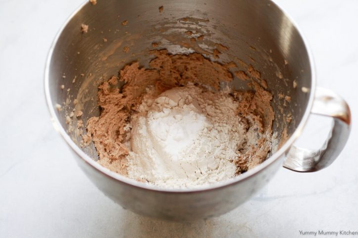 Flour and baking soda are added to creamed butter, sugar, and egg for vegan chocolate chip cookies. 