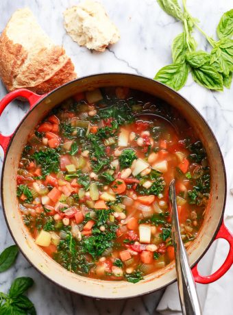 Healthy winter white bean and kale vegetable soup recipe in a red Le Creuset Dutch oven.