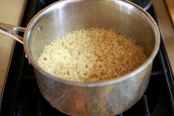 Quinoa has just finished cooking in a saucepan on the stove. 