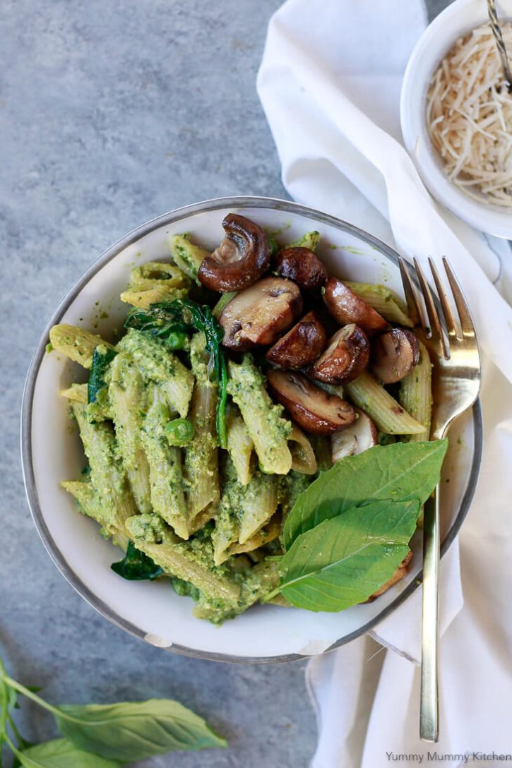 Pea pesto penne pasta in a white bowl with mushrooms and fresh basil. This vegan pesto pasta is a delicious lunch or dinner recipe. 