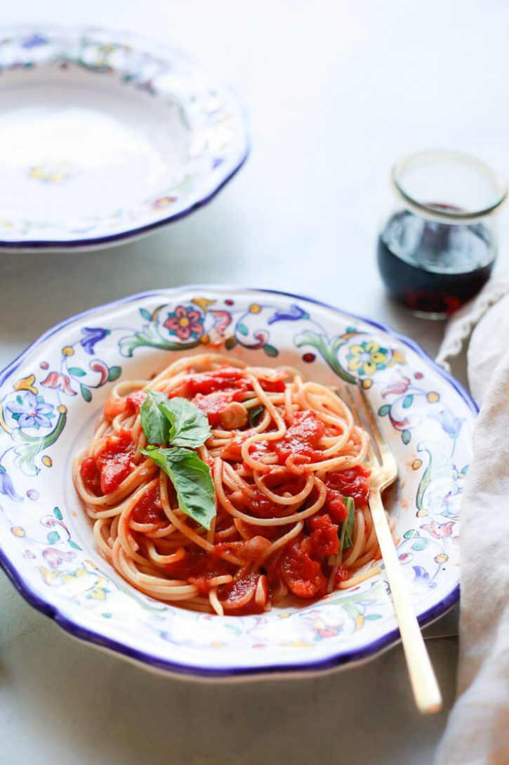 An Italian pottery bowl filled with spaghetti with pomodoro sauce and fresh basil. 