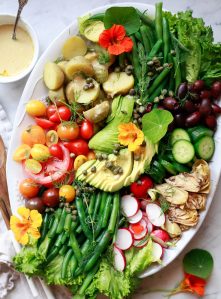 A beautiful white oval platter with vegan colorful Nicoise salad.