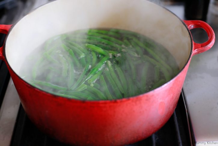 Green beans boil in a large red pot. 