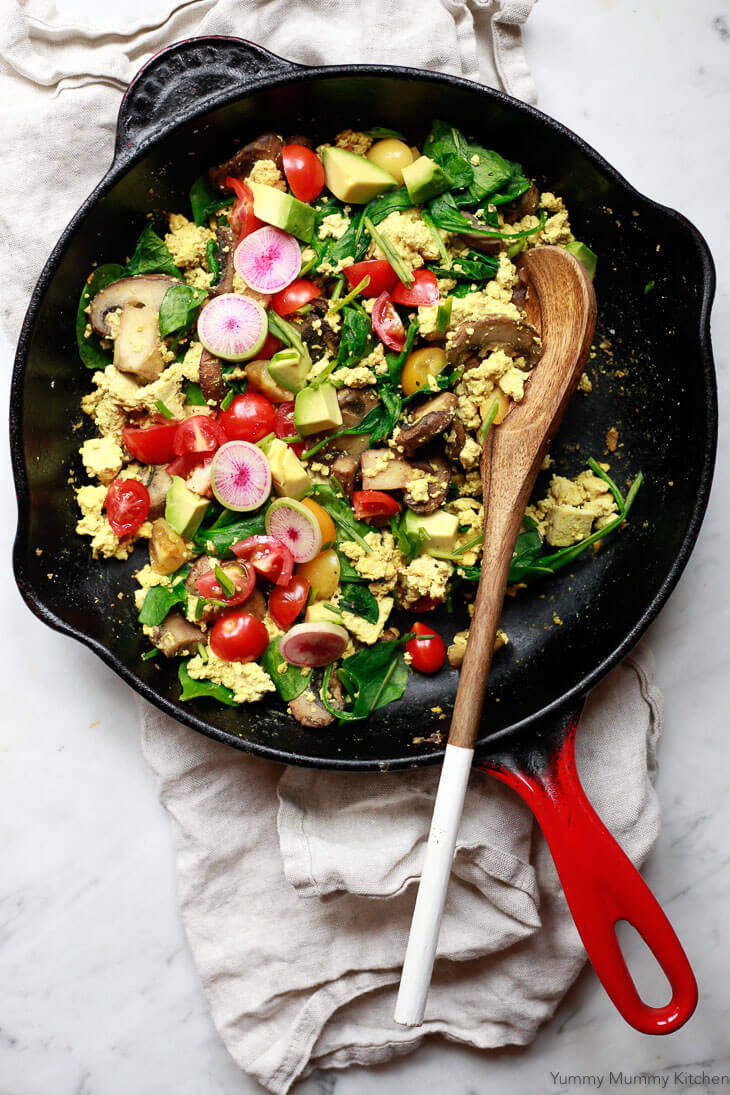 A red le Creuset skillet filled with vegan tofu scramble with spinach and vegetables. 