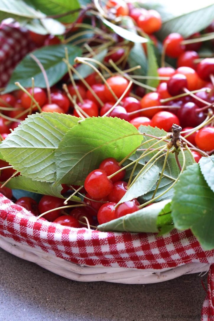 A red gingham basket filled with freshly picked cherries. 