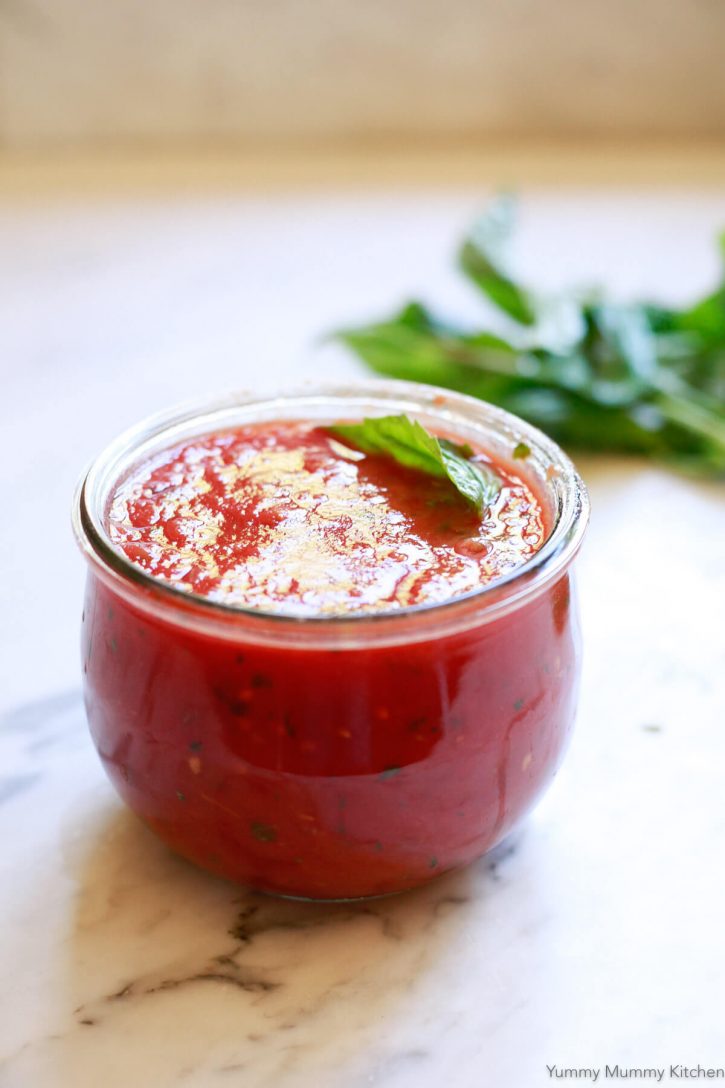A glass Weck jar filled with bright red homemade pizza sauce. 