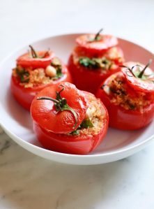 A dish filled with baked stuffed vegetarian tomatoes with quinoa and spinach.